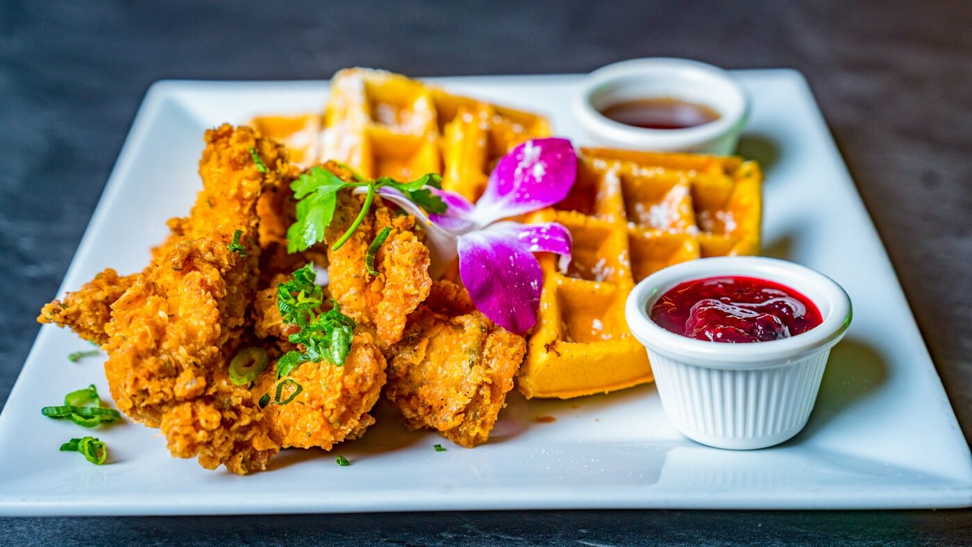 Fried chicken and waffles with an orchid, syrup and berry sauce