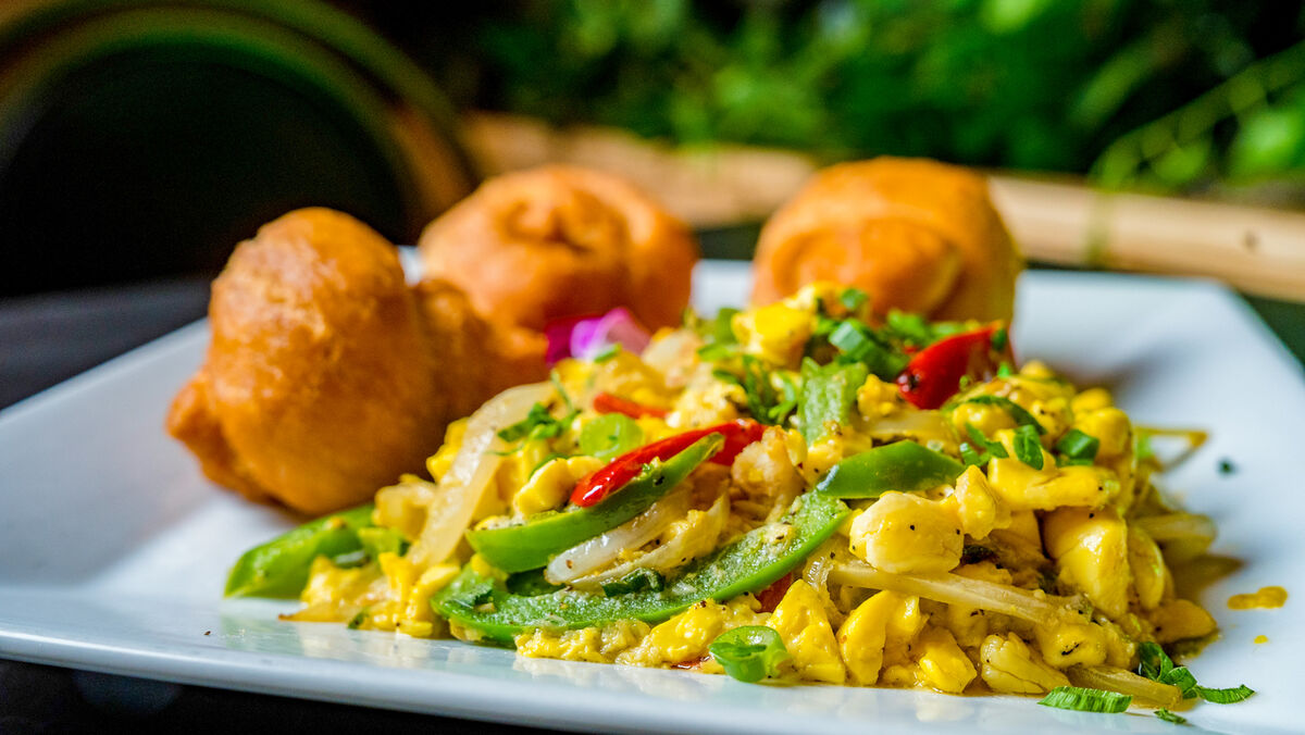 Ackee and saltfish with fried festival dumplings on a white plate